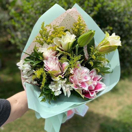Buquê Camponesa com lírios rosas e lírios brancos frescos, folhagens verdes e embalagem elegante com laço de fita, arranjo delicado e sofisticado para presentear